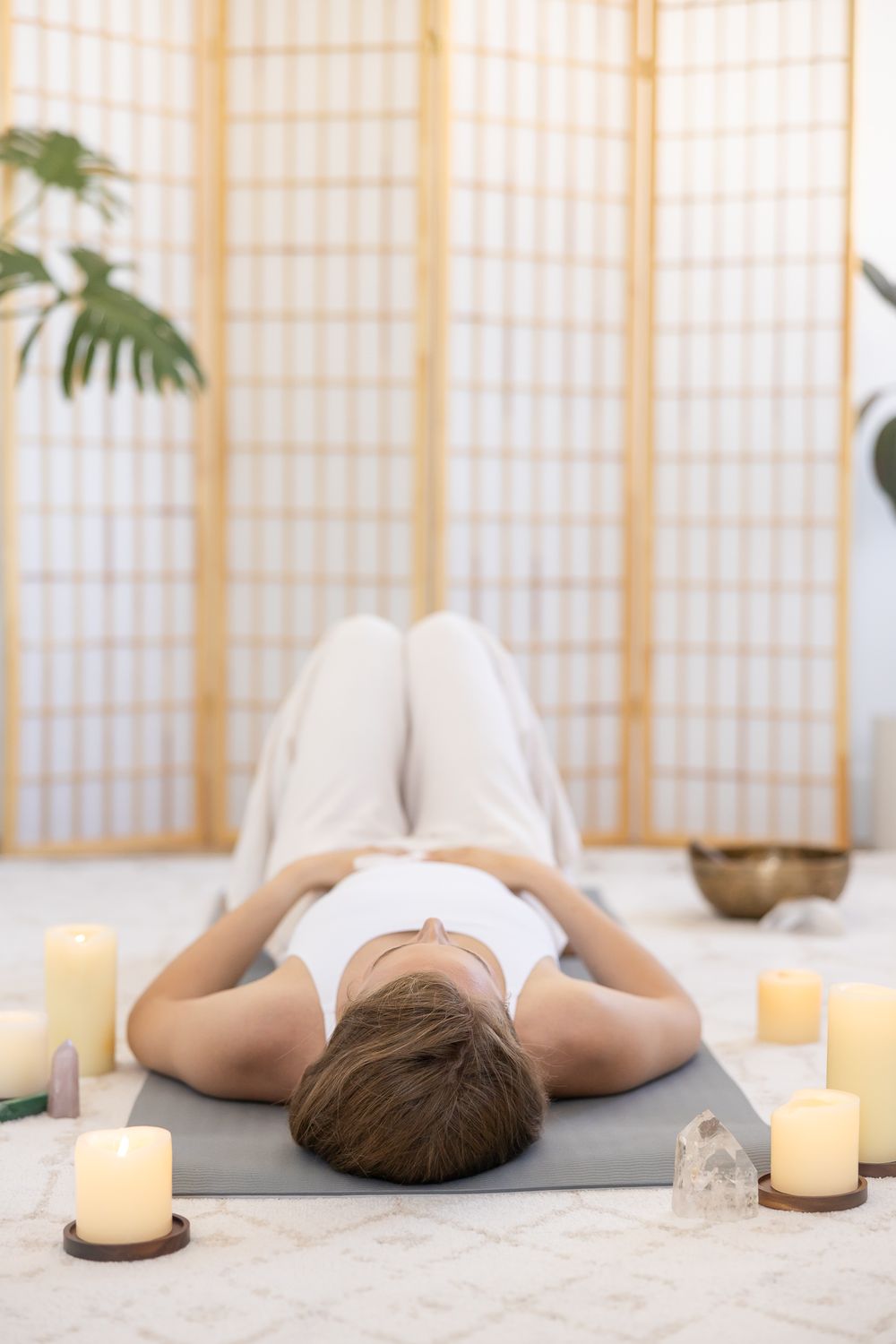 woman health coach laying on floor hands on belly, candles & crystals in soft natural light studio for branded stock photo Bellingham WA