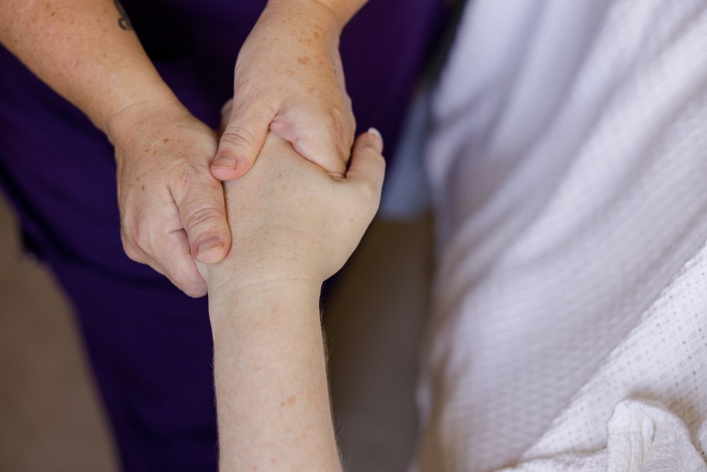 female massage therapist massaging hand of woman during treatment session in Bothell, WA for branding stock photo