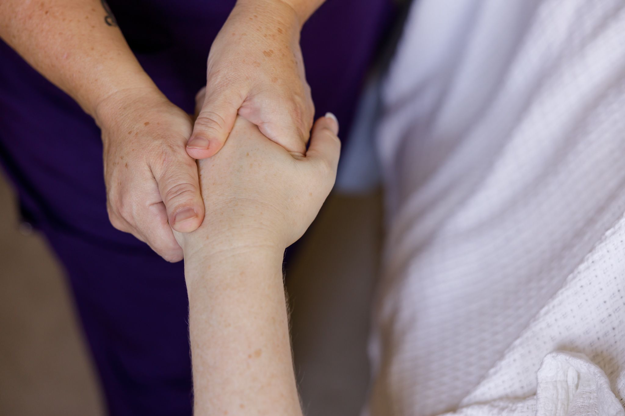 female massage therapist massaging hand of woman during treatment session in Bothell, WA for branding stock photo