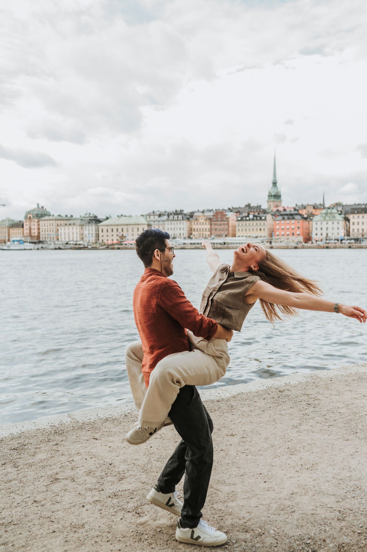 Elegant couple poses in stone archway with floral arrangement and mountain view.