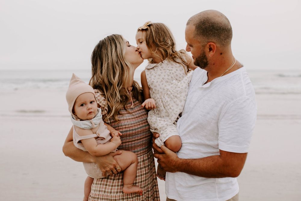 Family shares intimate moment together on a misty beach at sunset.