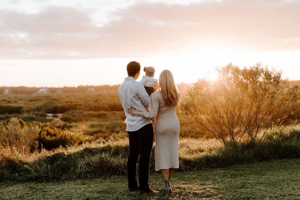 A couple sharing an intimate sunset moment on a hilltop overlooking nature.
