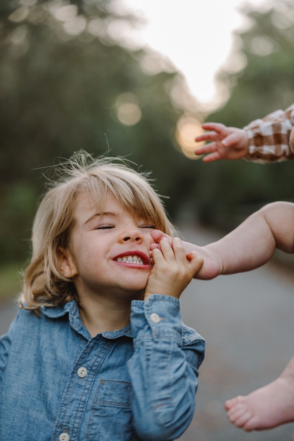 A child in denim showing pure joy and laughter during a candid outdoor moment.