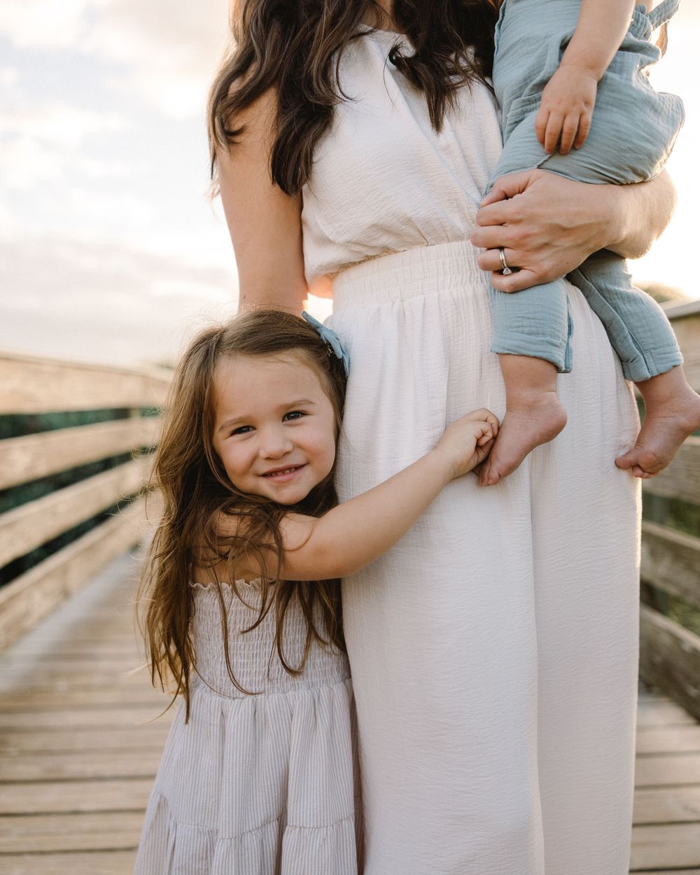 A series of cropped photos showing a mother in a white dress holding a small child against a warm sunset background.
