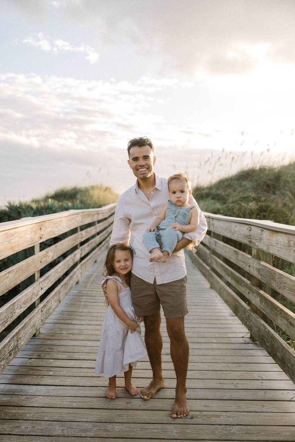 Family sharing joyful moments together while walking on a wooden boardwalk during golden hour.