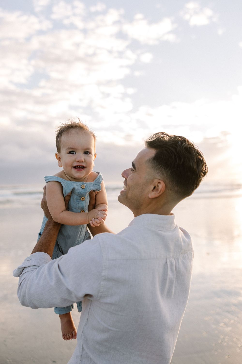 A series of heartwarming moments captured at sunset showing a parent in white shirt lifting and playing with a baby in blue.
