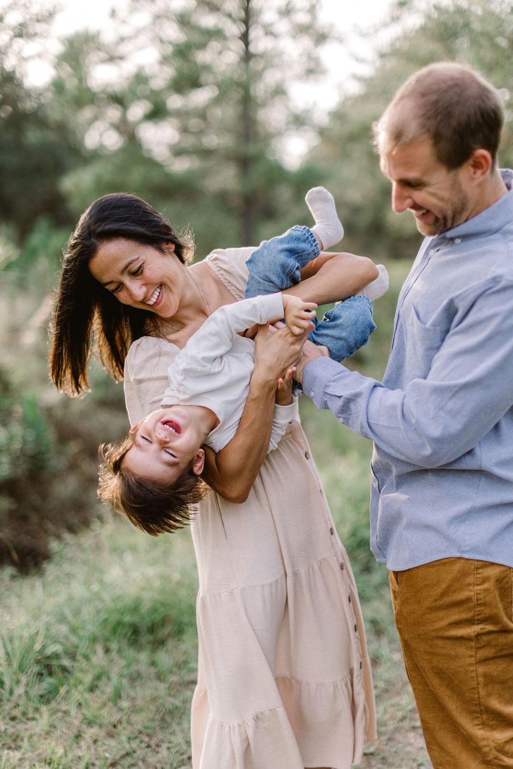 A playful family moment captured outdoors among pine trees.