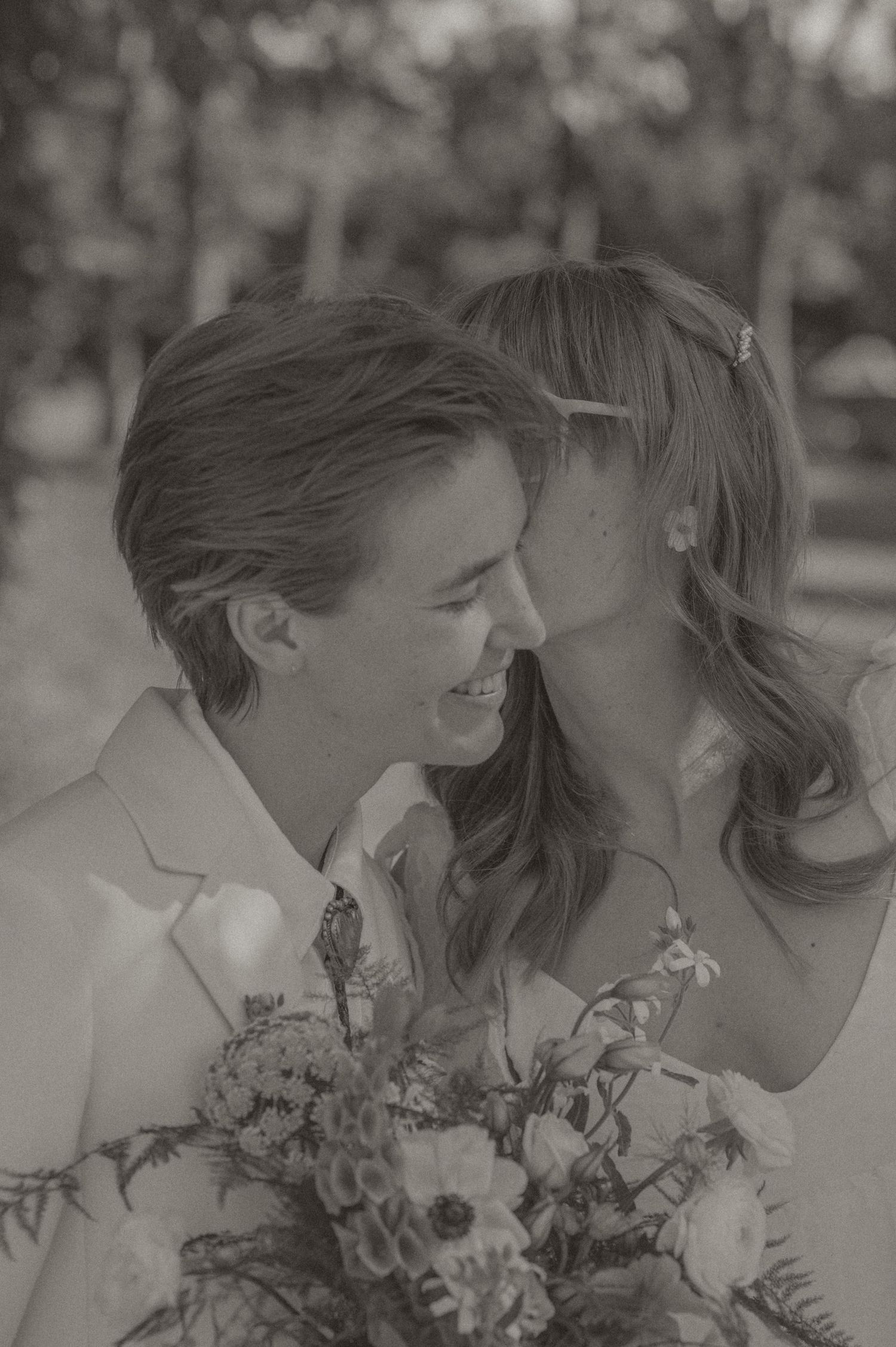 Black and white photo by samantha campbell of wedding attire displayed in a venue, with tuxedo and white gown visible on windows.