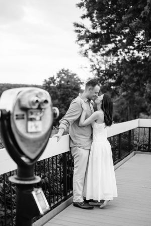A romantic moment captured next to a vintage viewfinder on an observation deck.