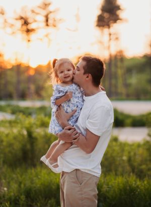Parent and child share a playful moment together in a sunny autumn forest at golden hour.