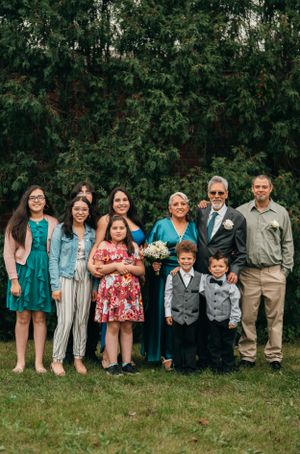 A group poses together outdoors against a backdrop of lush green trees during a special celebration.