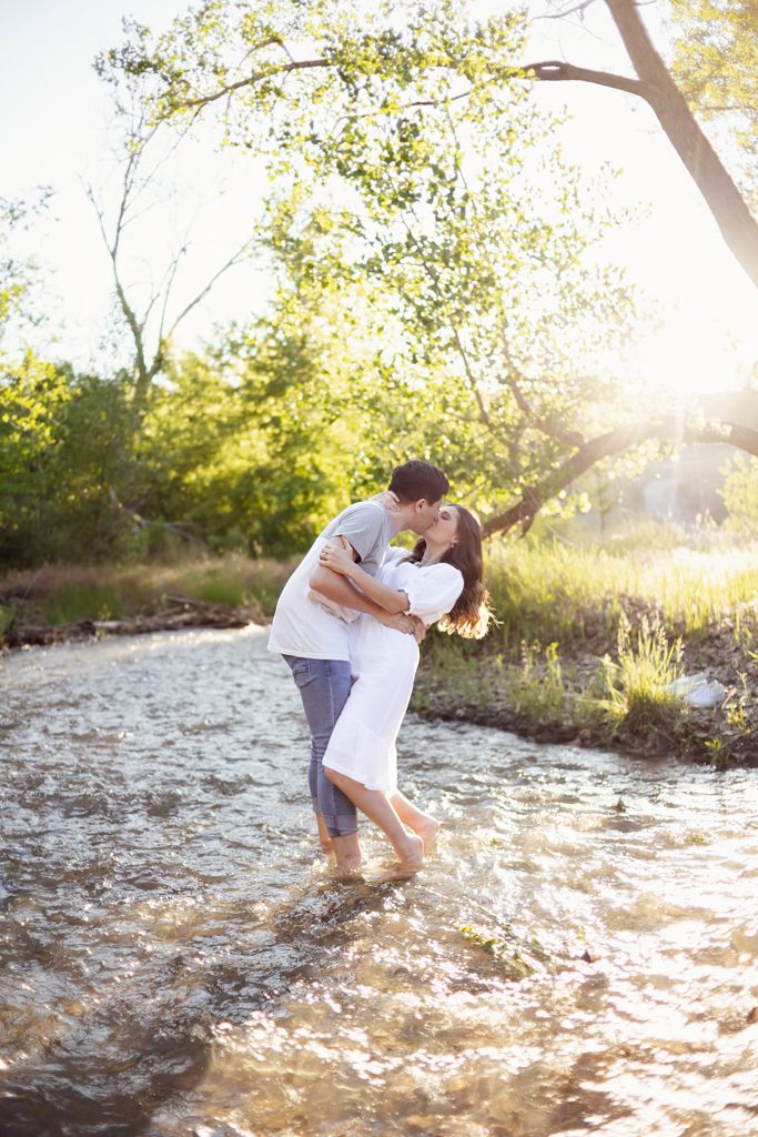 engaged couple kissing while standing in river