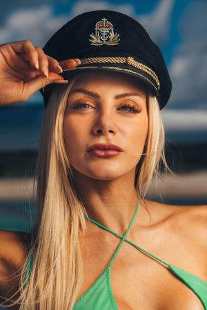 A close-up portrait series showing a person in a naval cap and green swimsuit against a blurred background.