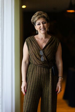 A person wearing a metallic striped jumpsuit stands confidently by a window.