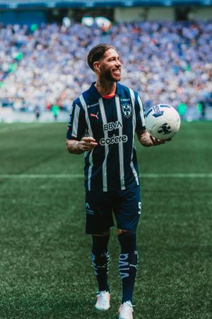 Soccer player in striped jersey holds ball on stadium field during match day.