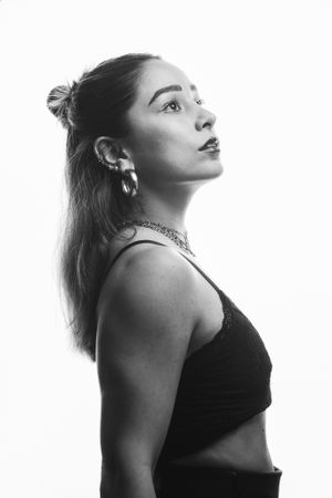Artistic black and white profile portrait of person in dark top against white background.