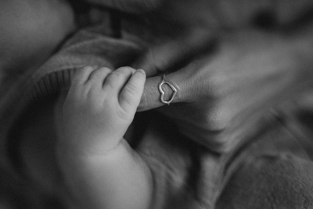 a new born holding his mom's finger at their new born photo session in Kent