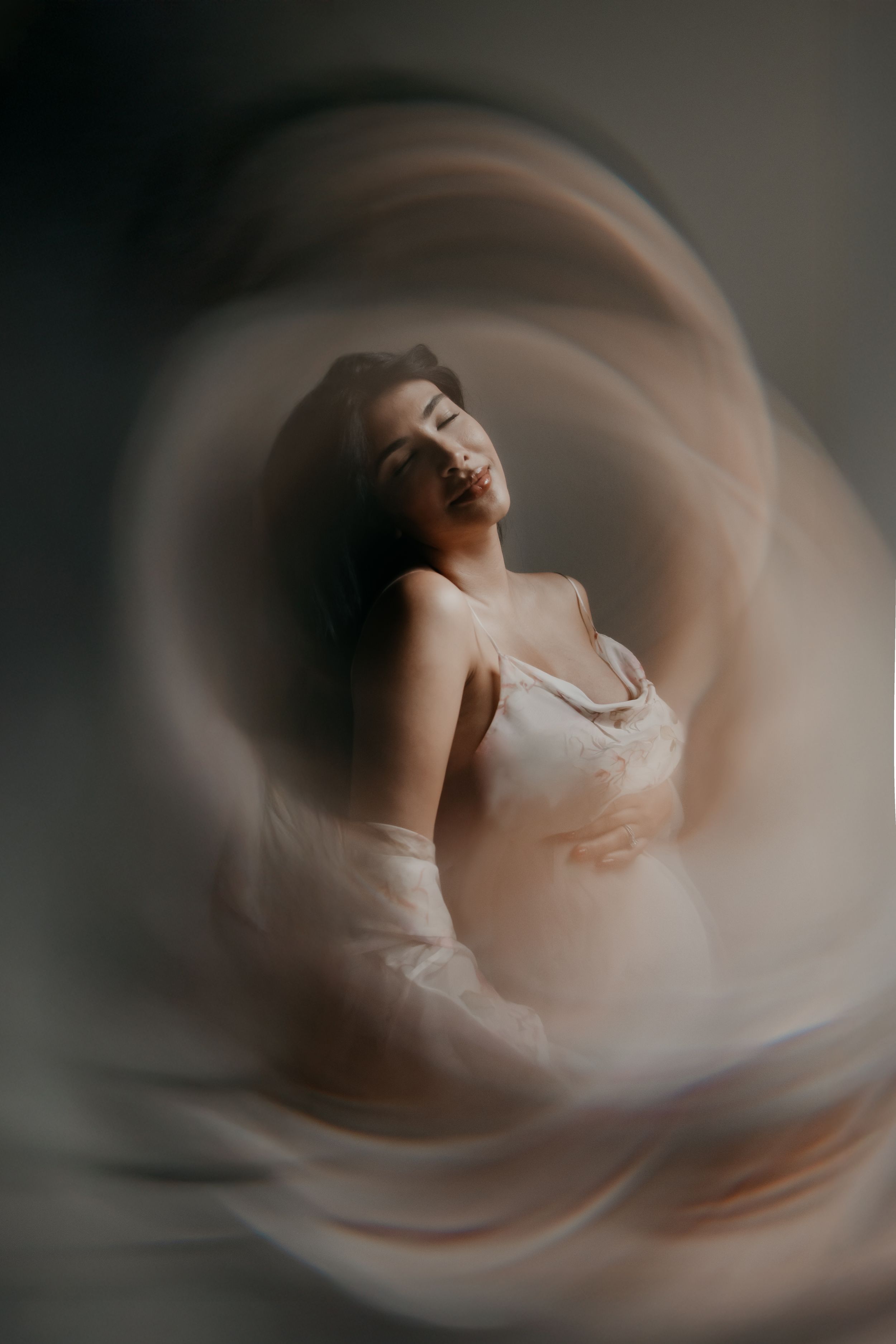 a pregnant woman posing with her eye closed and a dreamy smile on her face during an in home maternity photo session in London