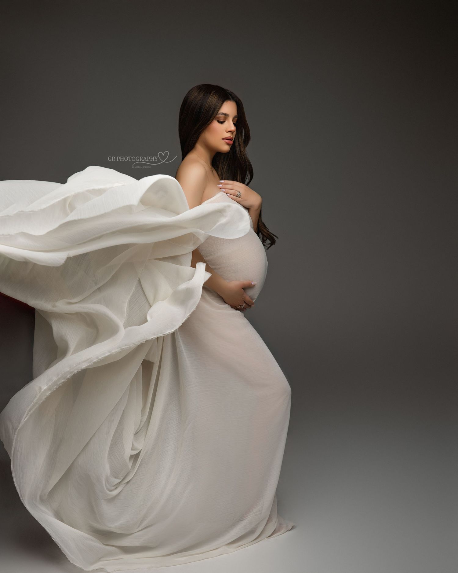 Dramatic maternity portrait in black dress against grey background with MOM typography.