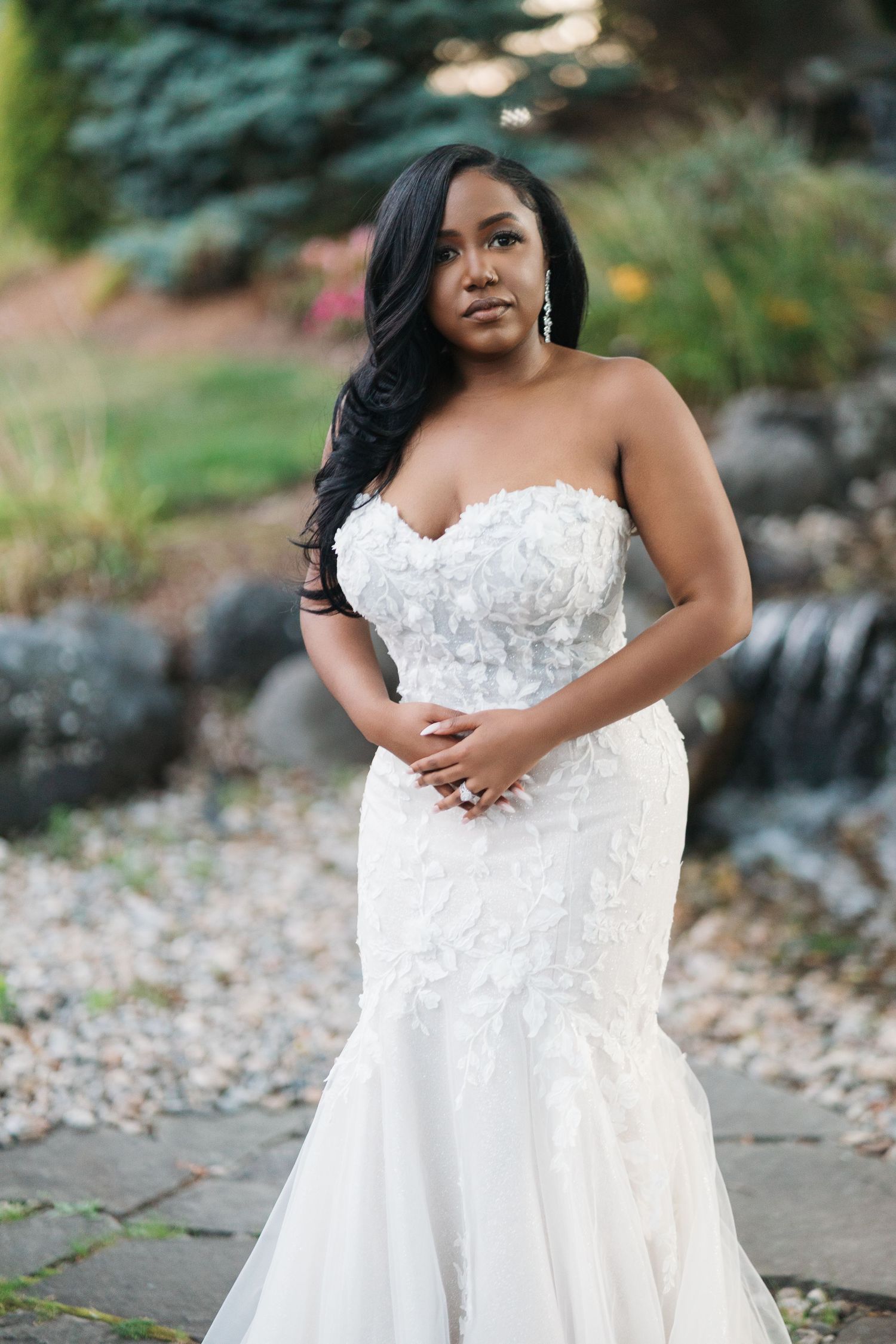 A stunning bridal portrait session featuring a white lace strapless wedding gown in an outdoor garden setting.