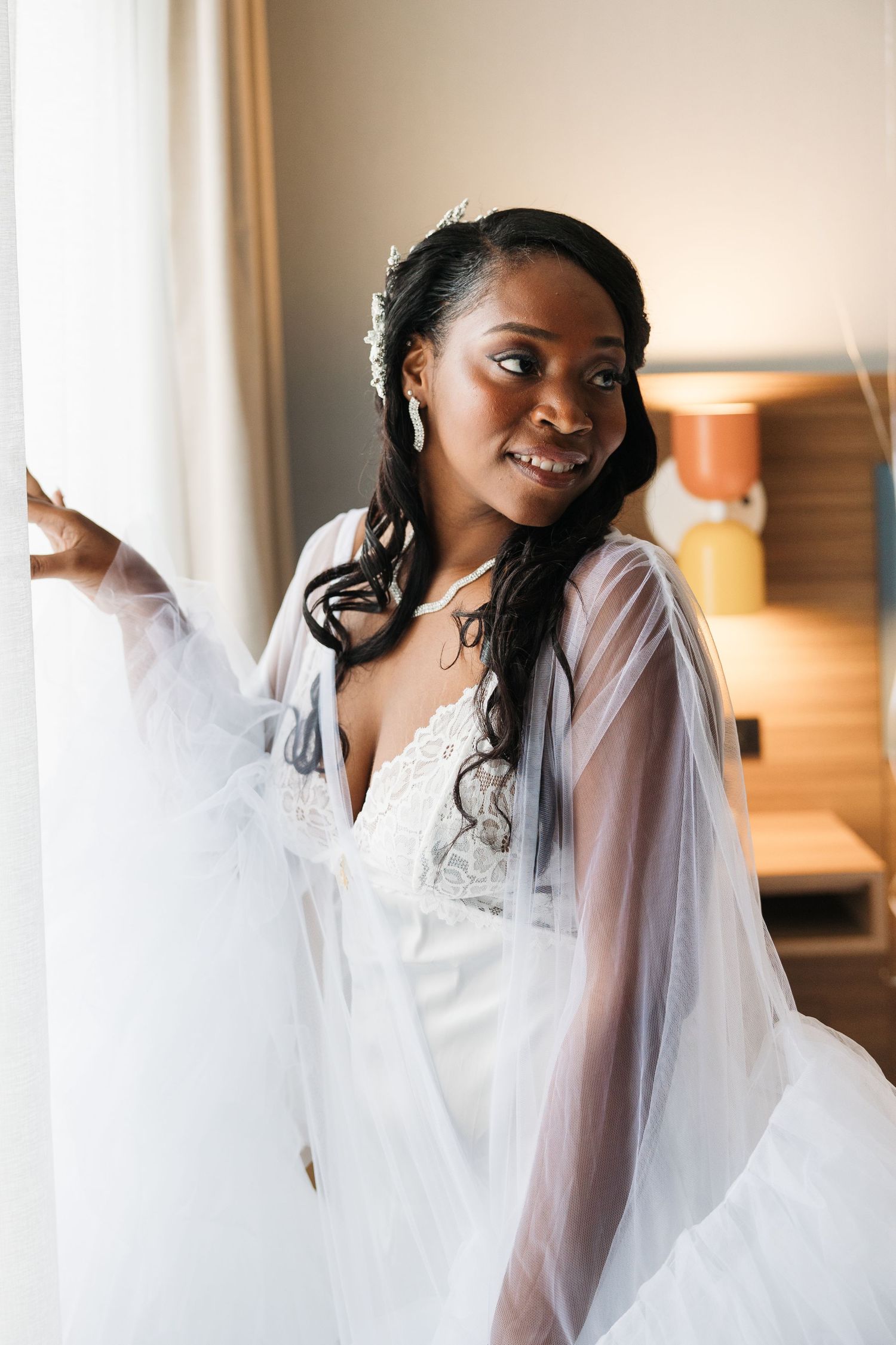 Joyful bride wearing white wedding dress and veil smiles radiantly during pre-wedding preparations.