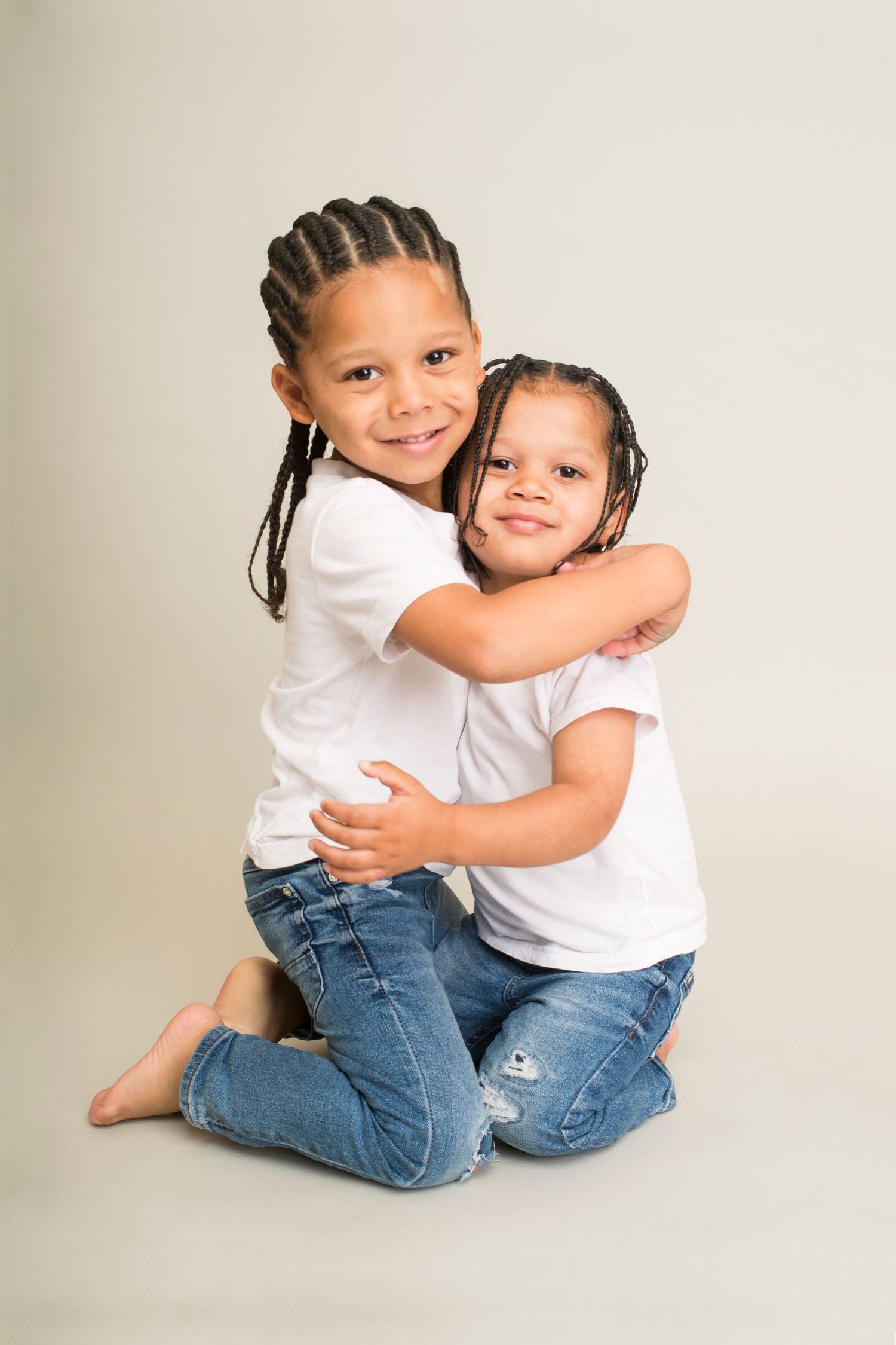 Brothers pose in blue jeans and white tee shirts for family photograph on light grey backdrop in Abigail's Studio High Wycombe