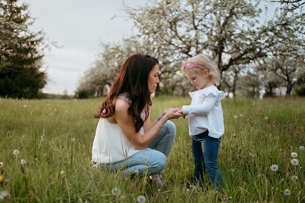 A couple shares an intimate moment together in a sunlit meadow filled with wildflowers.