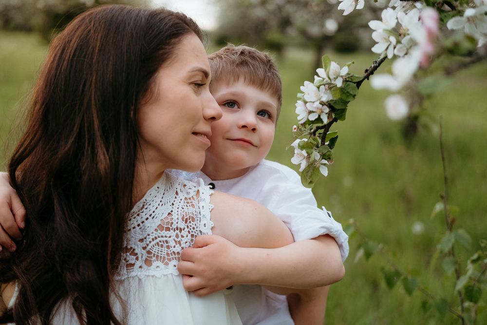 A tender spring moment captured between parent and child among blooming white flowers in a garden setting.