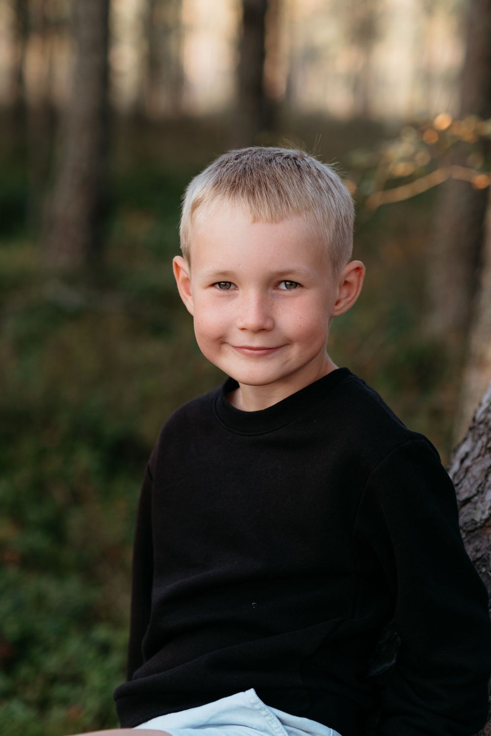 A series of four outdoor portrait photos showing a child in a black sweater with trees in the background.