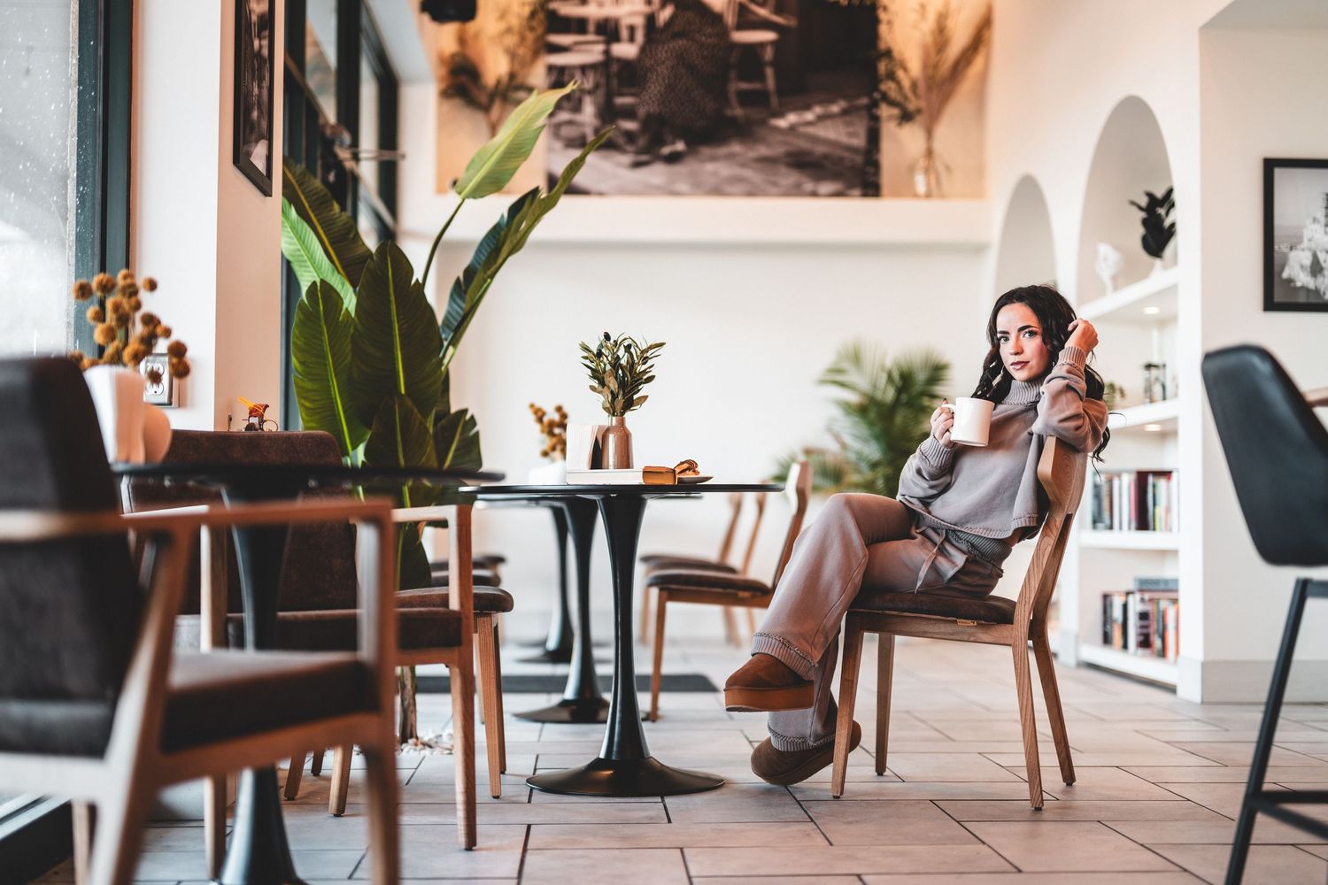 Modern coffee shop interior with wooden ceiling, framed wall art, counter service area and communal table seating.
