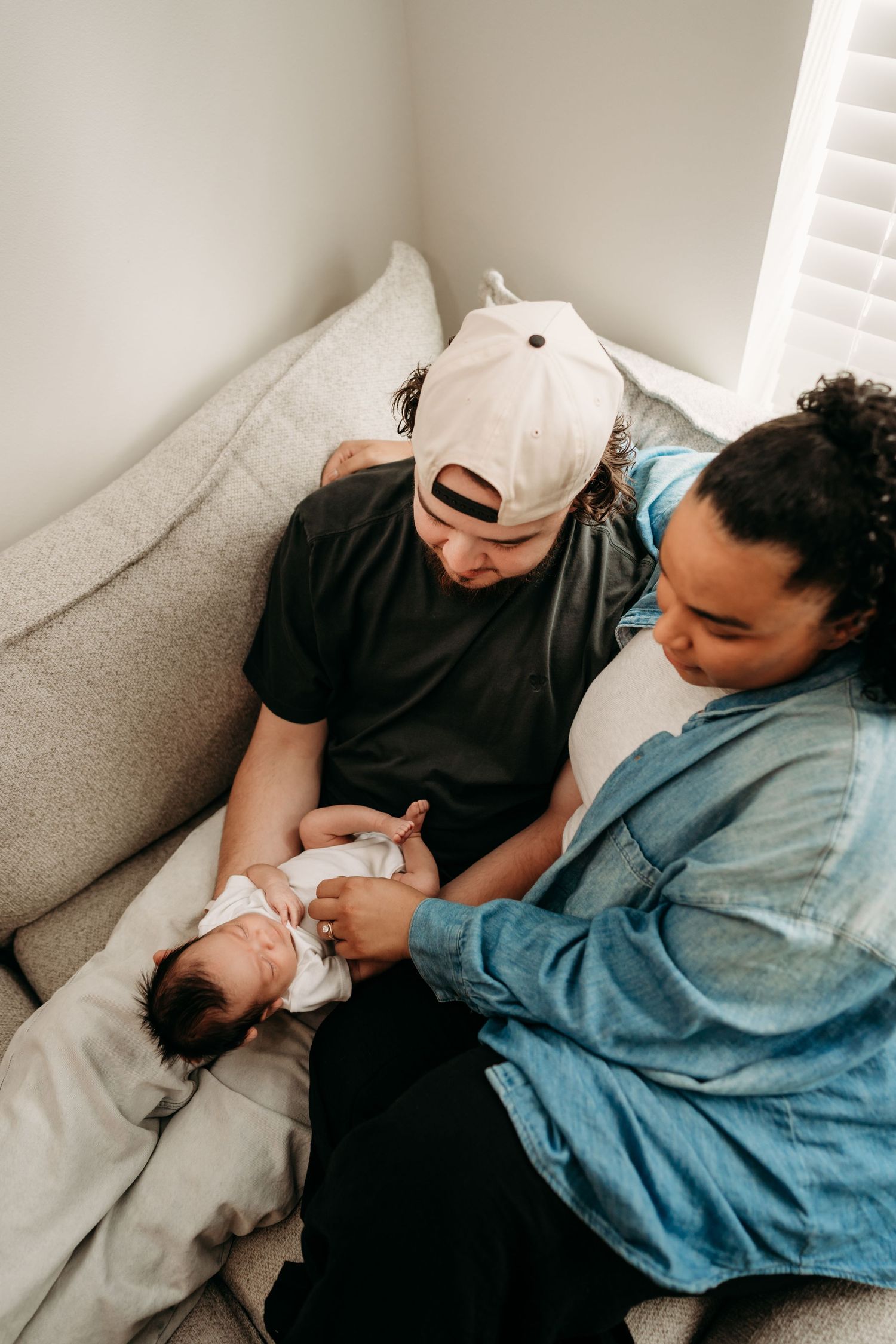 A series of tender moments showing a baby being held and comforted on a couch during in home lifestyle newborn photo session in Tacoma, Wa.