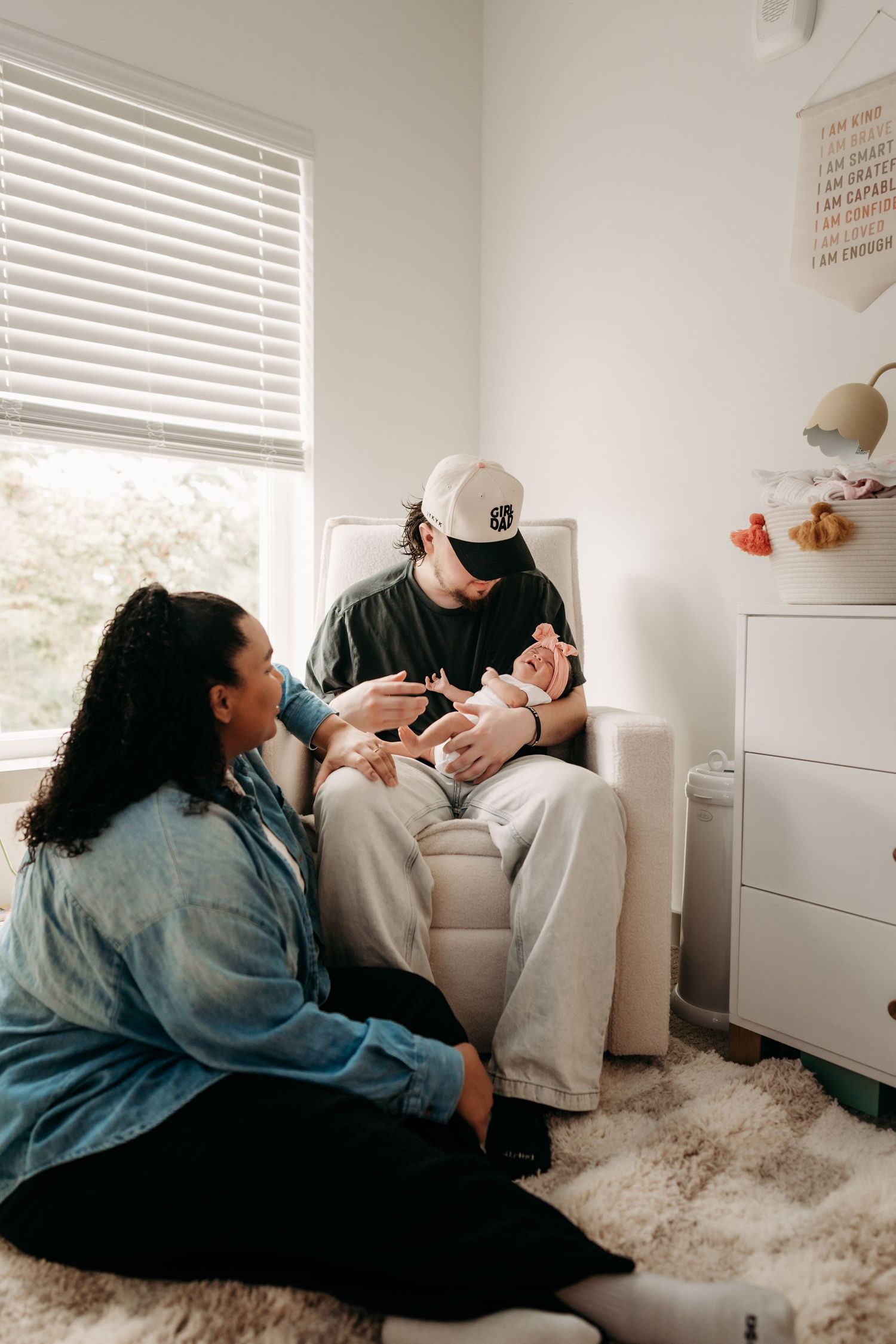 A couple sits together in a cozy nursery room while holding their newborn baby during in home newborn photo session in Tacoma, WA