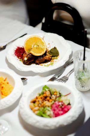 Beautifully plated dishes with colorful garnishes served on white plates at a fine dining restaurant.