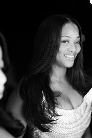 A woman in a sparkly white dress smiles warmly in a black and white portrait.