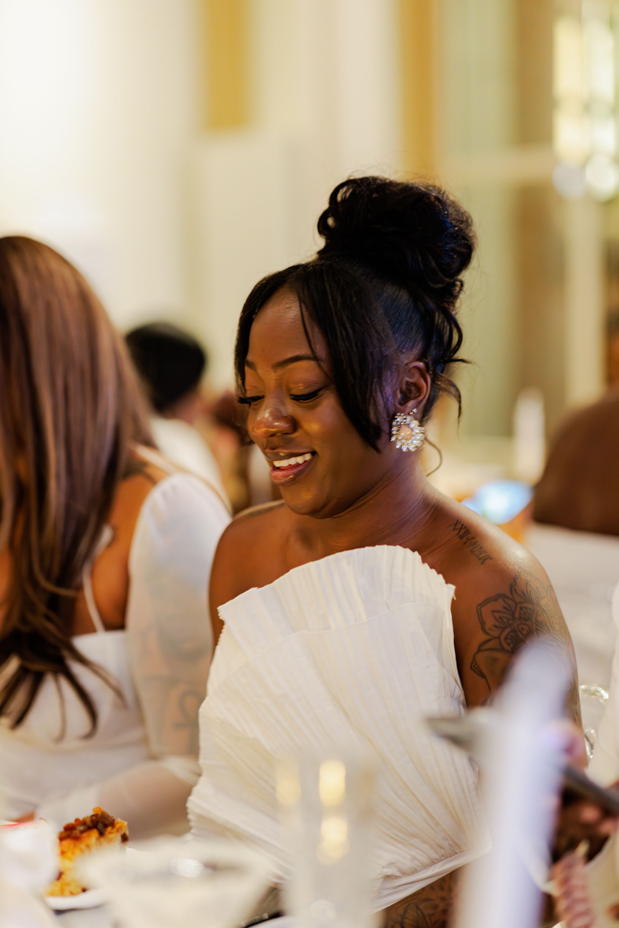 A woman in a white strapless dress laughs joyfully during a celebration.