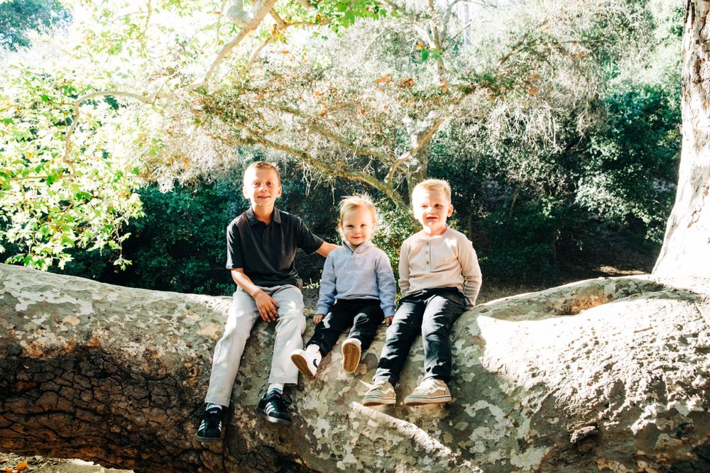 Family members sitting together on large rocks in a wooded outdoor setting.