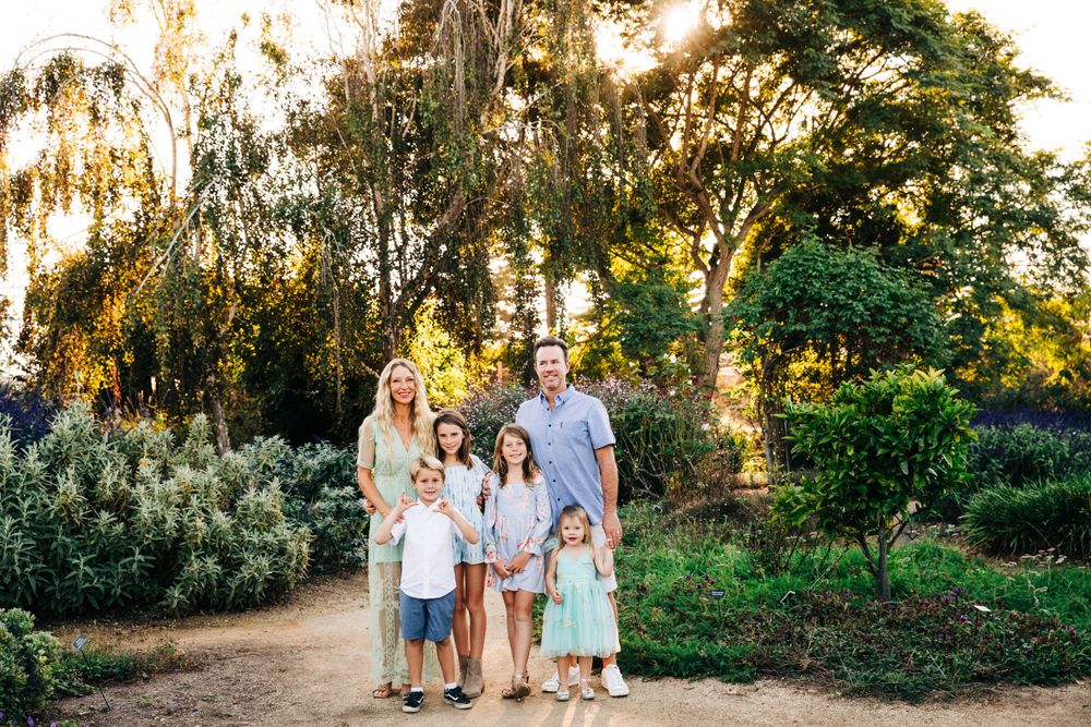 Family walking together on a sunlit garden path during golden hour.