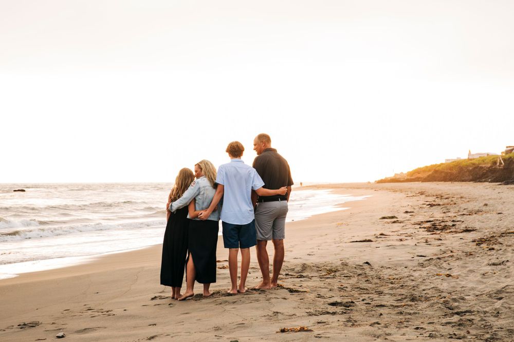 Family embracing while walking along sunset beach shoreline.