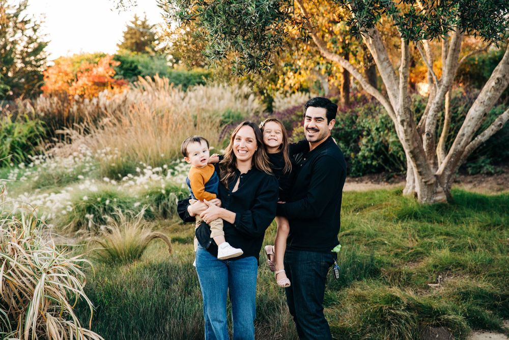 Family enjoying a playful moment together outdoors during golden hour in a natural setting.