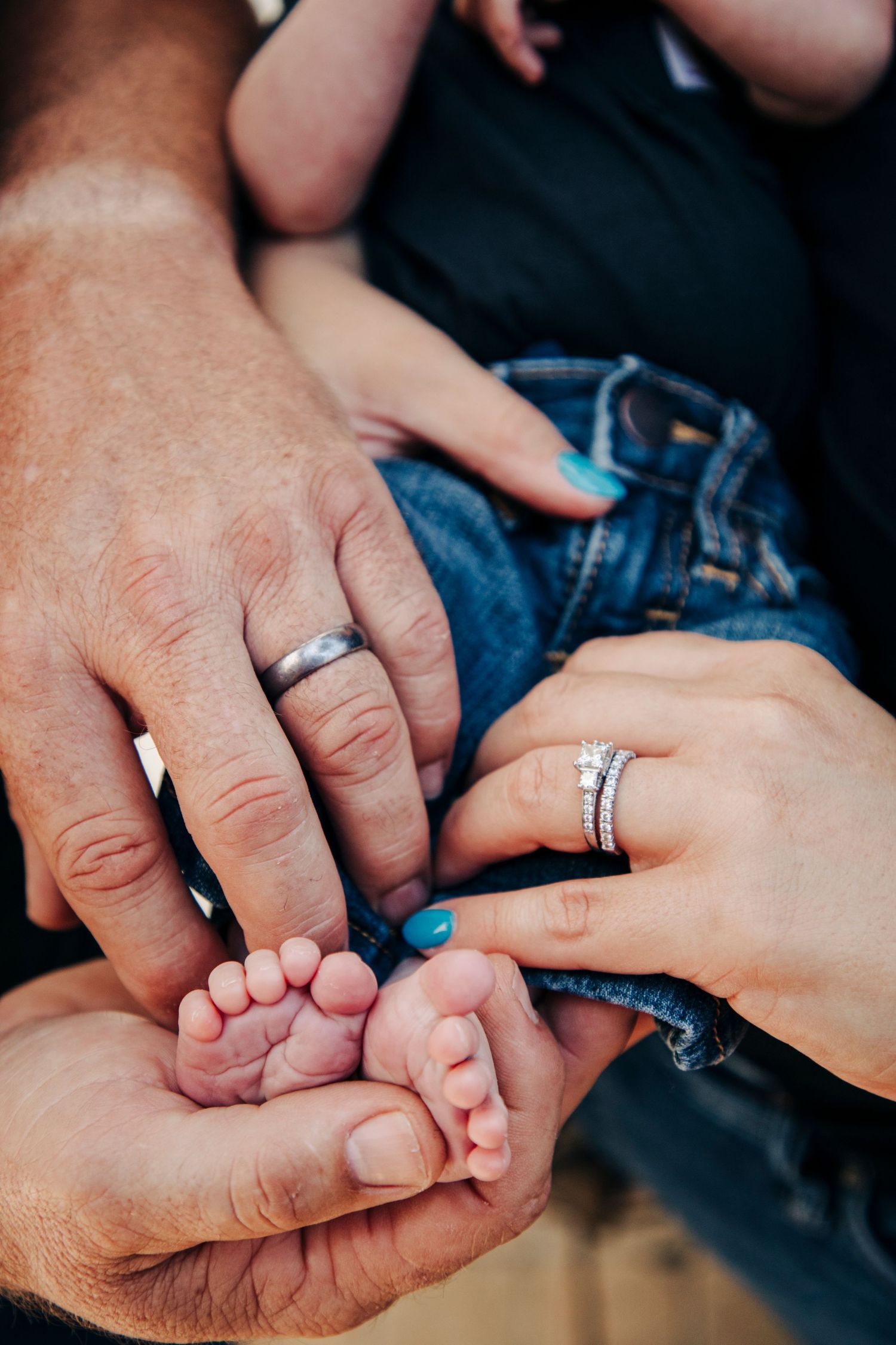 Multiple hands gently holding and touching tiny baby feet.