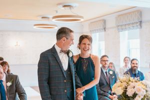 Joyful candid moments between wedding guests at bright indoor reception venue.