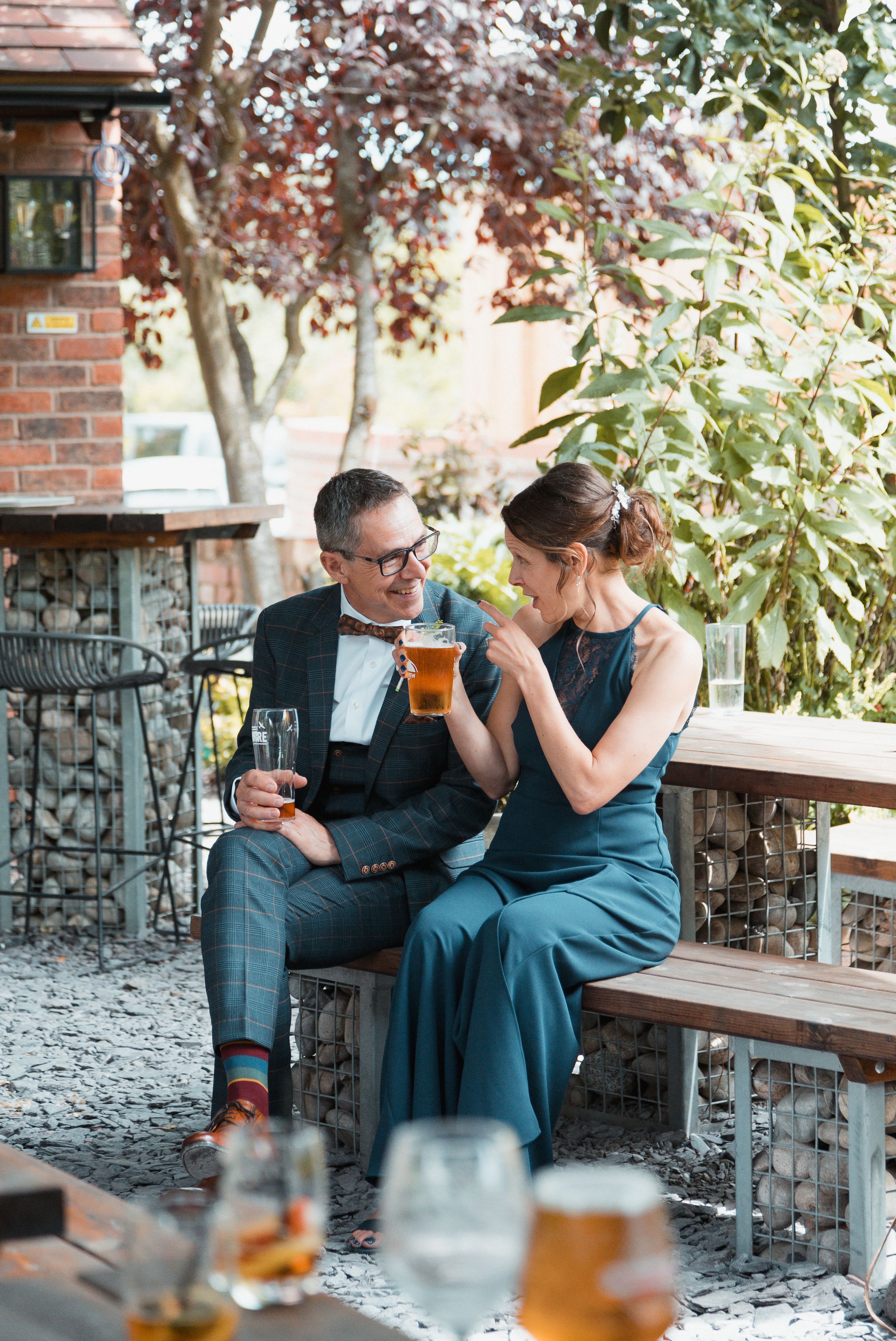 A couple enjoys drinks together on an outdoor patio with brick and stone details.