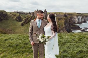 Coastal wedding scene with dramatic cliffs and ocean backdrop.
