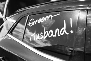 Wedding car windows decorated with white handwritten messages.