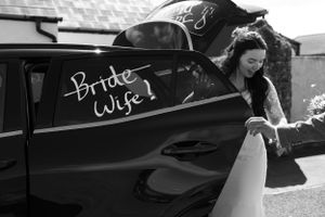 Black wedding car with decorative white text written on windows.