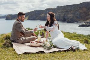 Romantic picnic setup on coastal cliff overlooking dramatic ocean views.