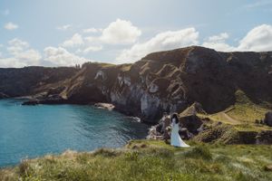 Dramatic coastal landscape with rugged cliffs and ocean views along a scenic coastline during sunset.