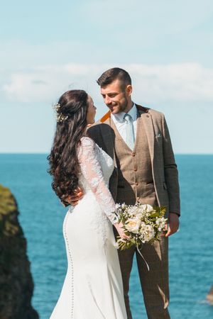 A coastal wedding ceremony with the couple posing against a stunning blue ocean backdrop.