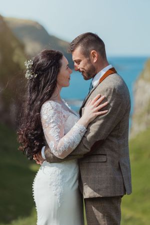 An intimate wedding moment captured on a coastal cliff with dramatic ocean views.