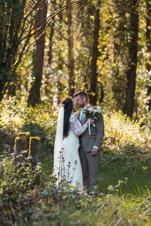 A romantic woodland wedding photoshoot with sunlight filtering through autumn trees.